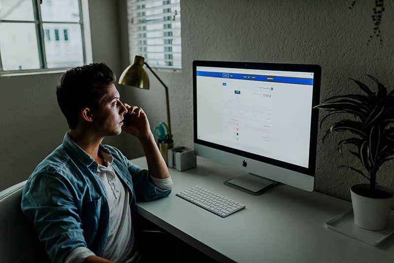 man on phone looking at computer screen