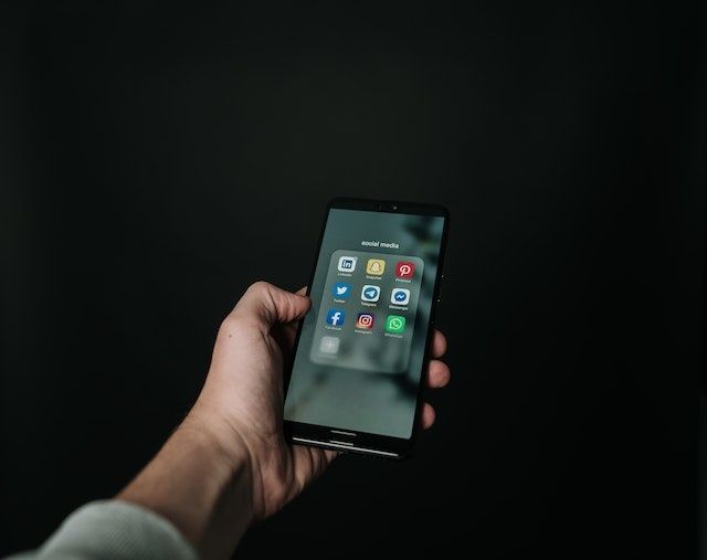 man holding a phone with multiple social media applications displayed